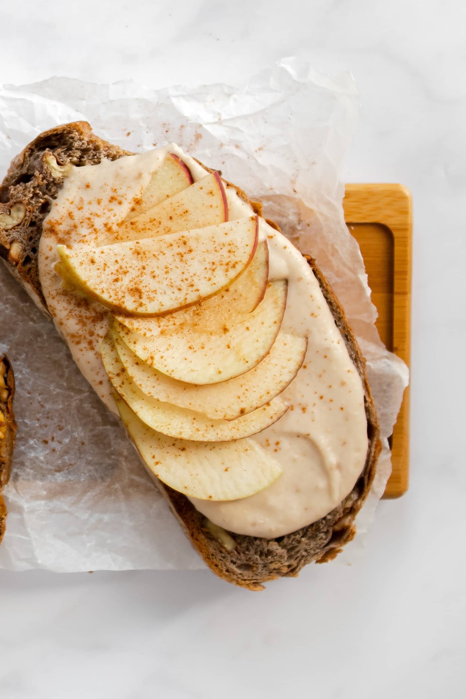 fines tranches de pomme sur une tranche de pain multigrain badigeonnée d'un déliceux beurre de pomme citronné maison