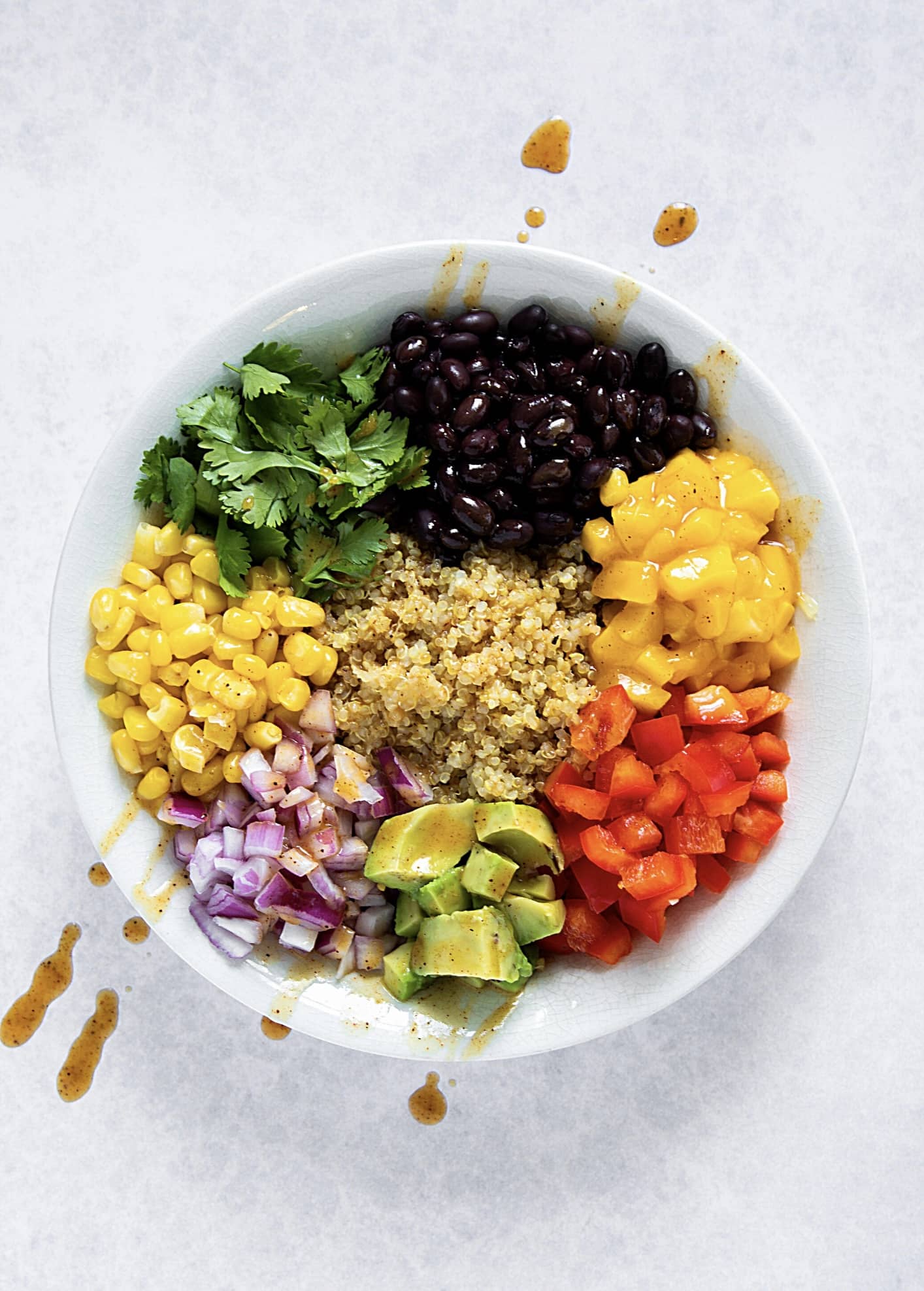 Salade colorée vivifiante avec quinoa, mais, herbes, haricot noir, poivron, avocat, oignon. jaune vert rouge mauve noir