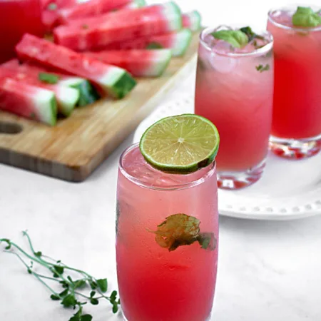 Verres rempli d'un breuvage rose avec bâtonnets de melon d'eau