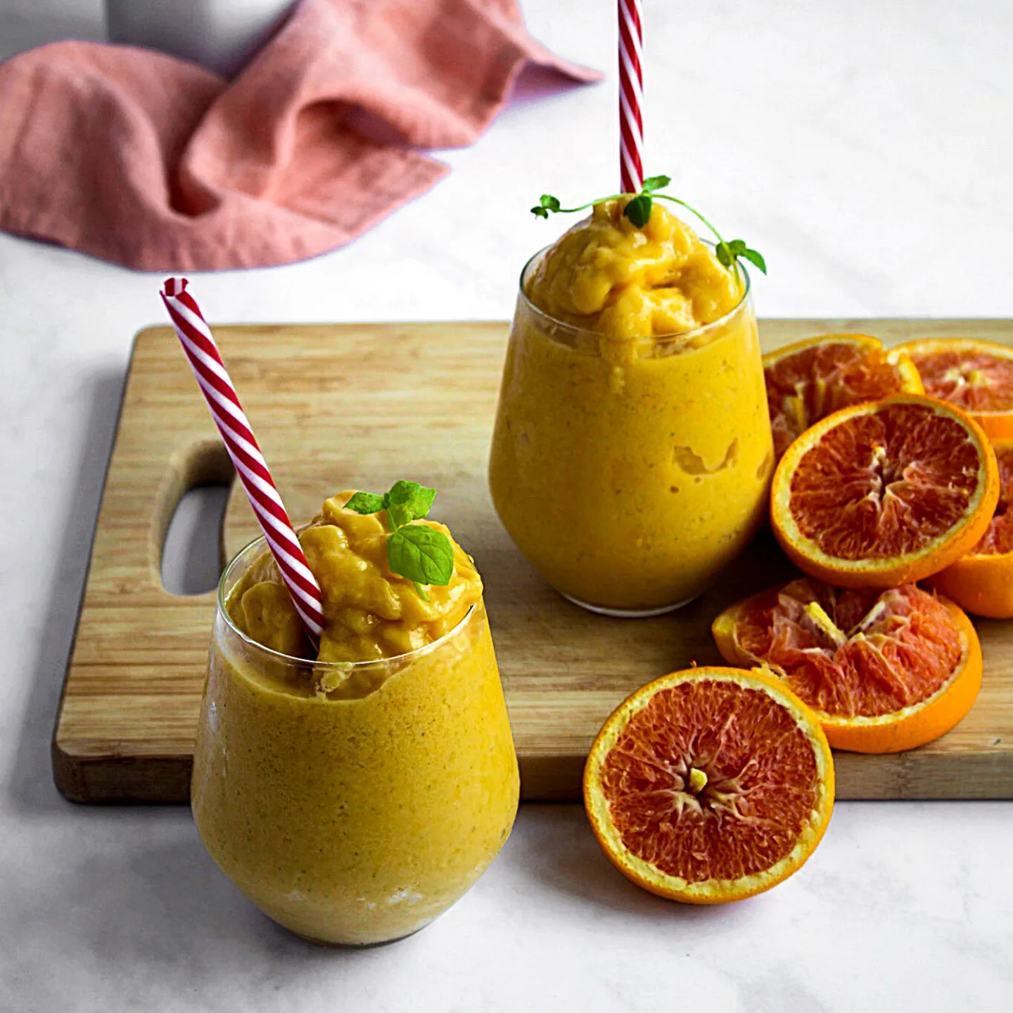 2 verres débordants de smoothie glacés jaunes à la mangue avec tranches d'oranges