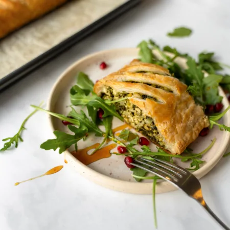Portion de feuilleté aux épinards dans une assiette avec roquette et grenade