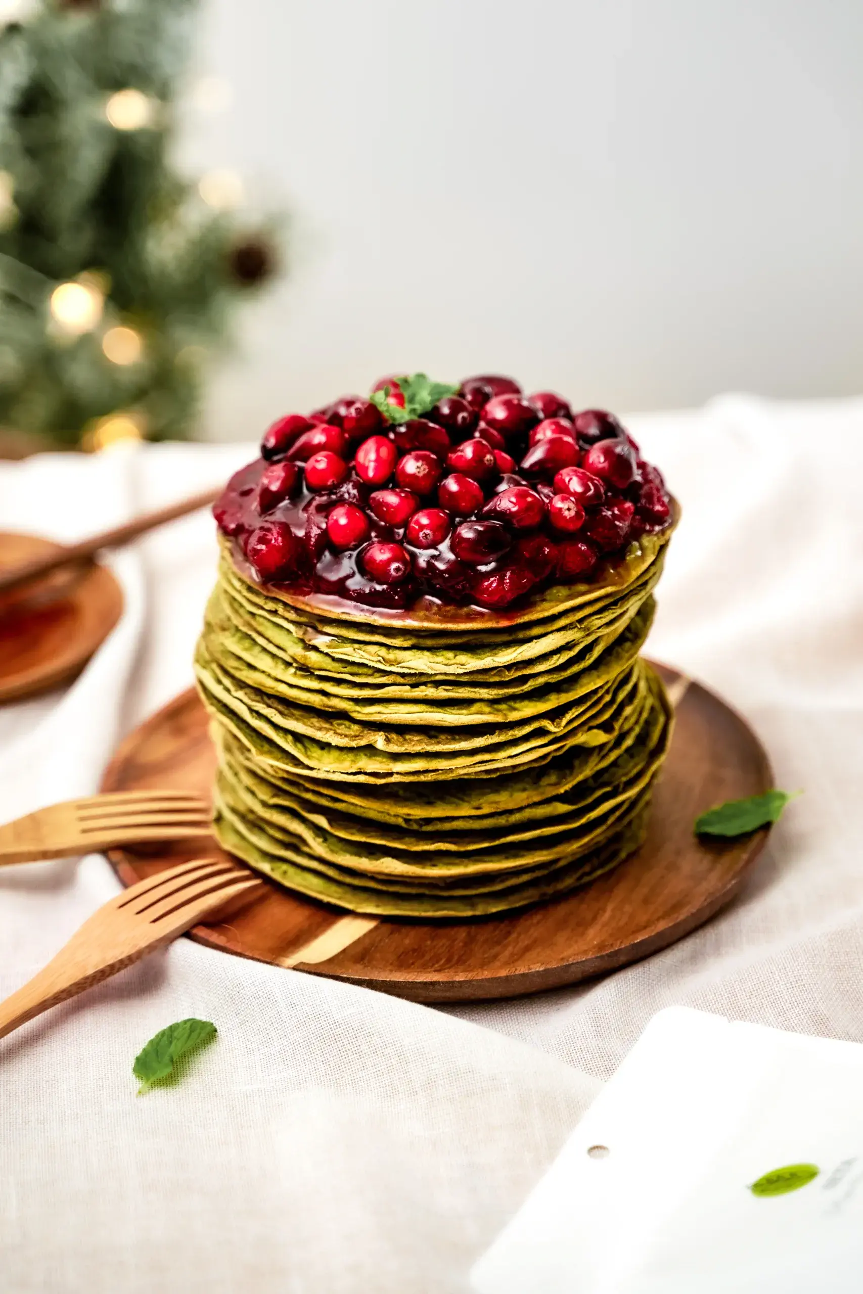 Étagé de dizaines de crêpes au matcha vertes avec des canneberges sur le dessus
