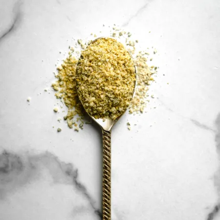 cuillère débordante de poudre de parmesan vegan jaune