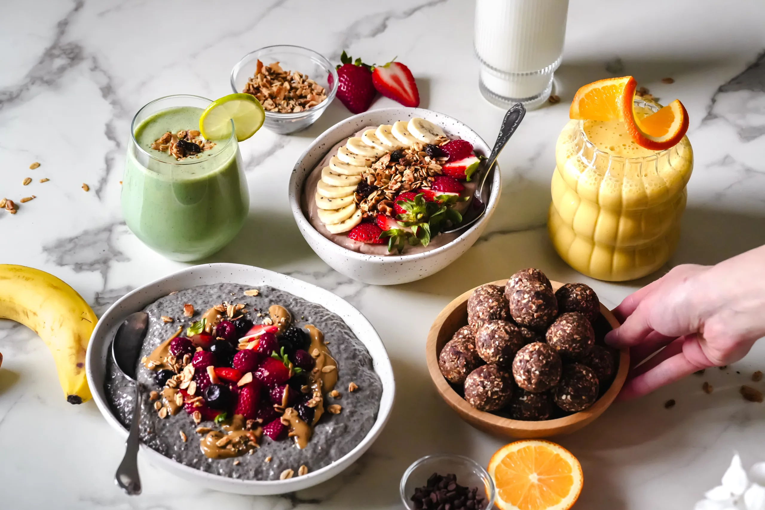 Table avec déjeuner, collations et une main qui dépose un bol de boules d'énergie