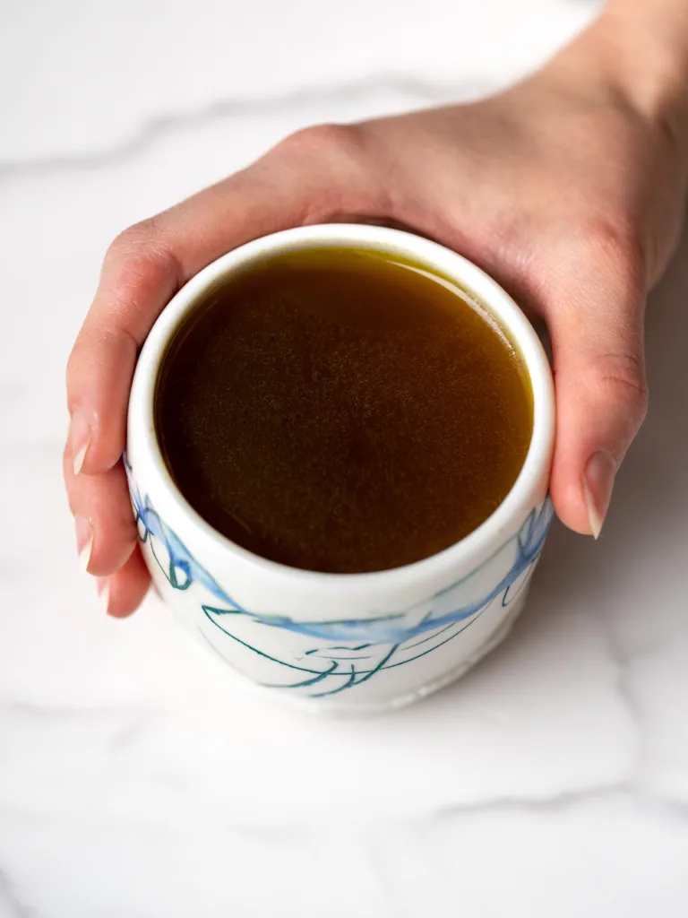 main qui tient un bol rempli de bouillon vitalité