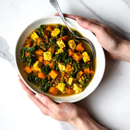 Bol de ragoût végétarien patate douce entre des mains