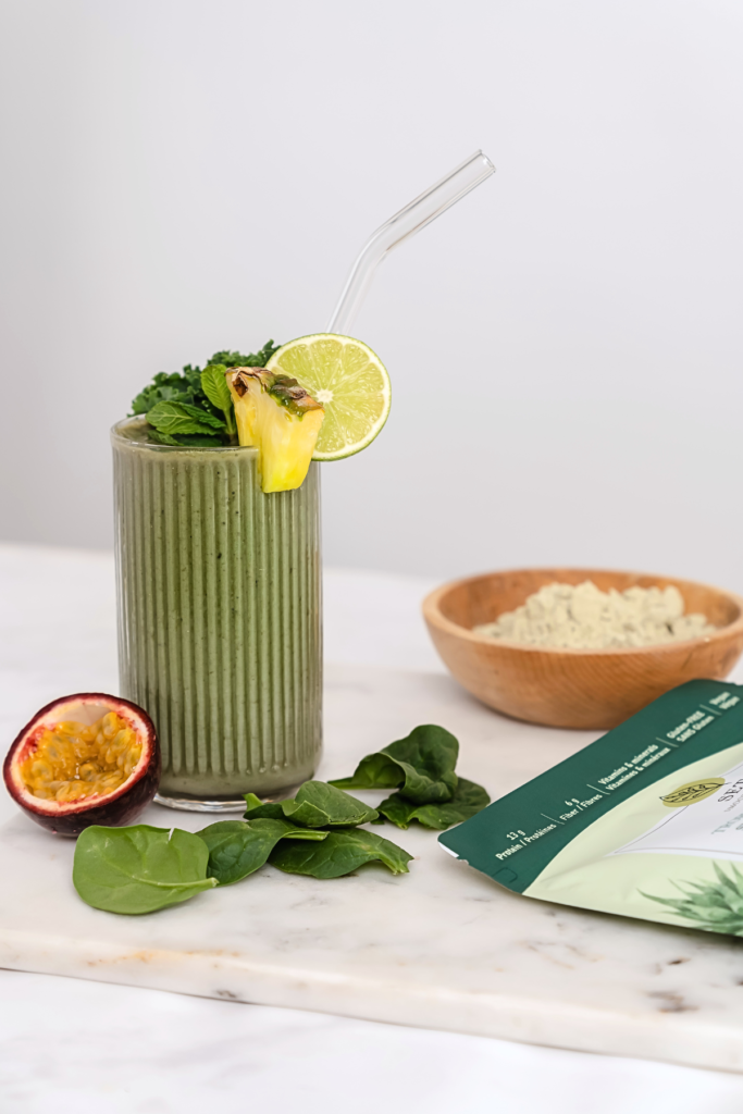 Verre de smoothie vert avec fruits tropicaux sur le dessus et le côté