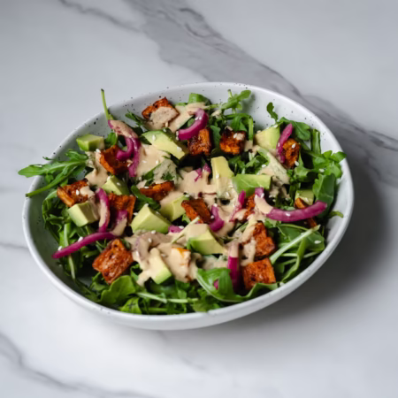 Grand bol de salade de patates douces rôties et avocat avec une vinaigrette aux arachides sur le dessus