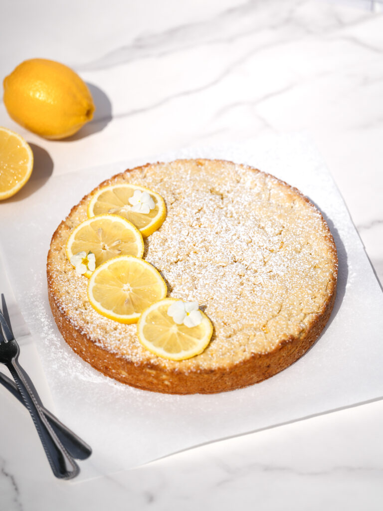 Gâteau au citron entier parfait pour l'heure du thé, recouvert de sucre à glacer et de tranches de citron en décoration