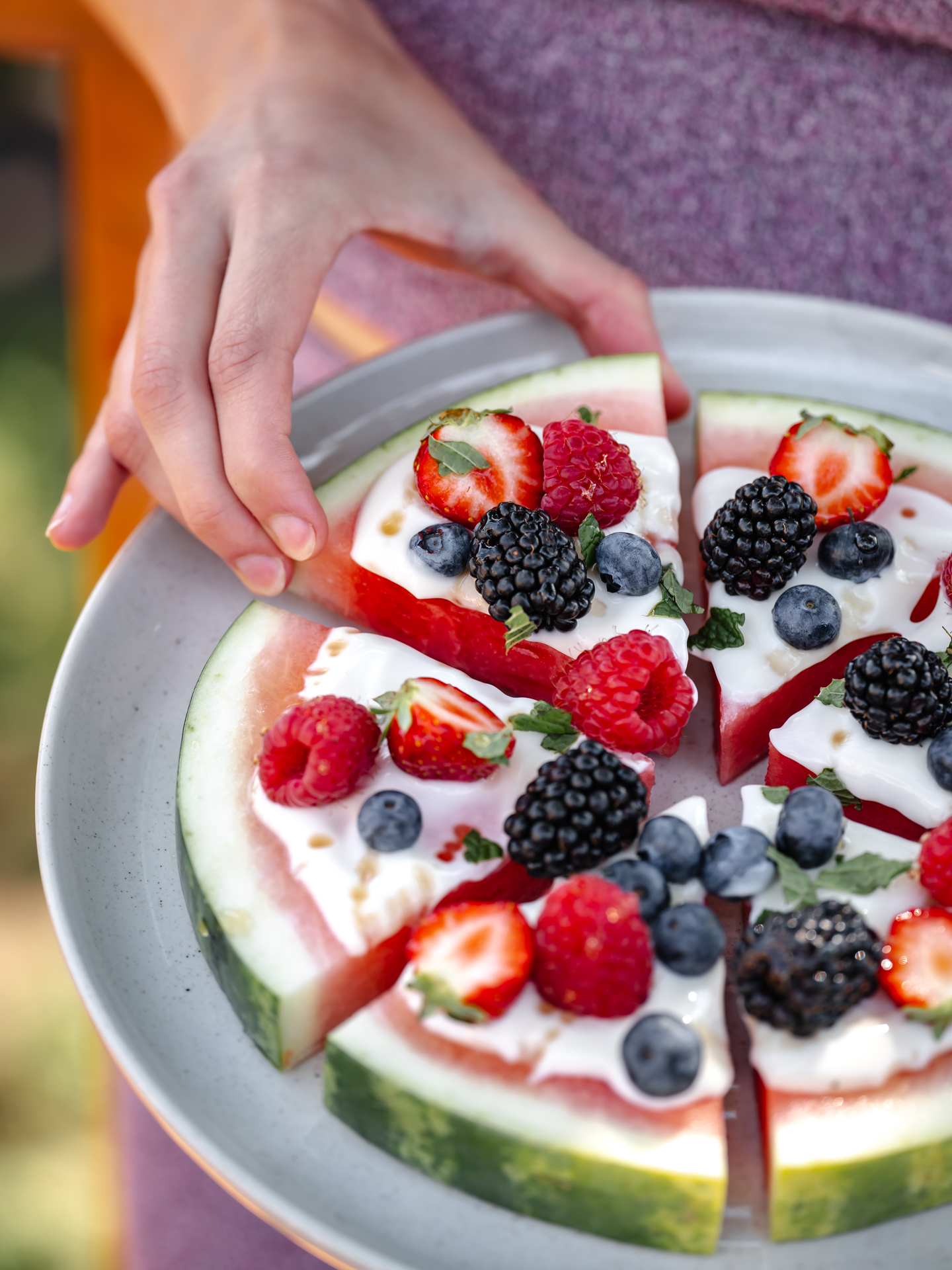 Anna se sert une pointe de pizza de melon d'eau recouverte de yogourt crémeux et de petits fruits savoureux