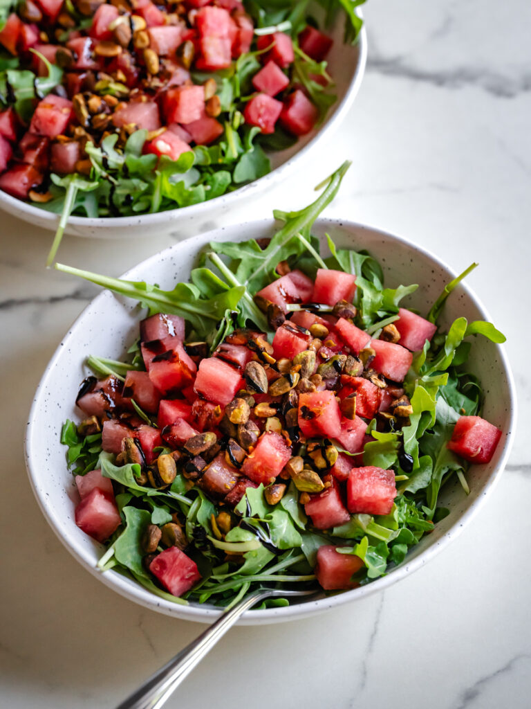 Bols de salade de melon d'eau fraîche, roquette et pistaches croustillantes