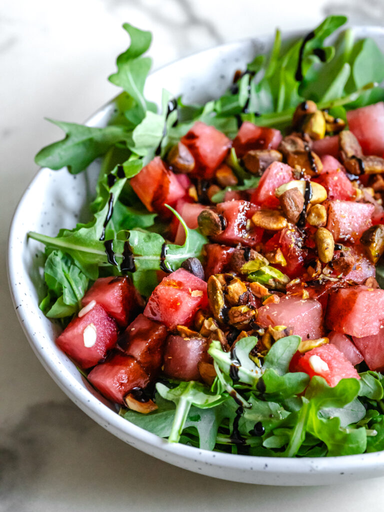 Bol de salade de melon d'eau fraîche, roquette et pistaches croustillantes