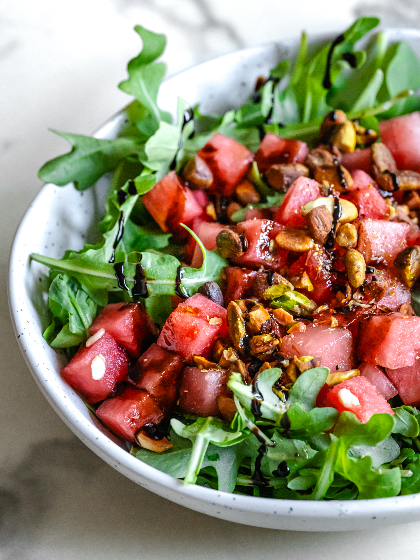 Bol de salade de melon d'eau fraîche, roquette et pistaches croustillantes
