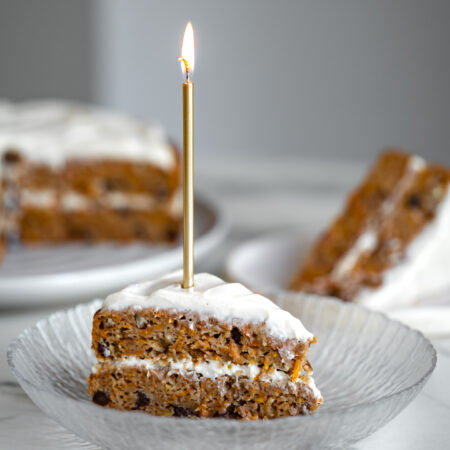 Une pointe généreuse de gâteau aux carottes santé sans sucre raffiné ni gras ajoutés avec une bougie allumée sur le dessus - Bonne fête à notre associé Antoine!