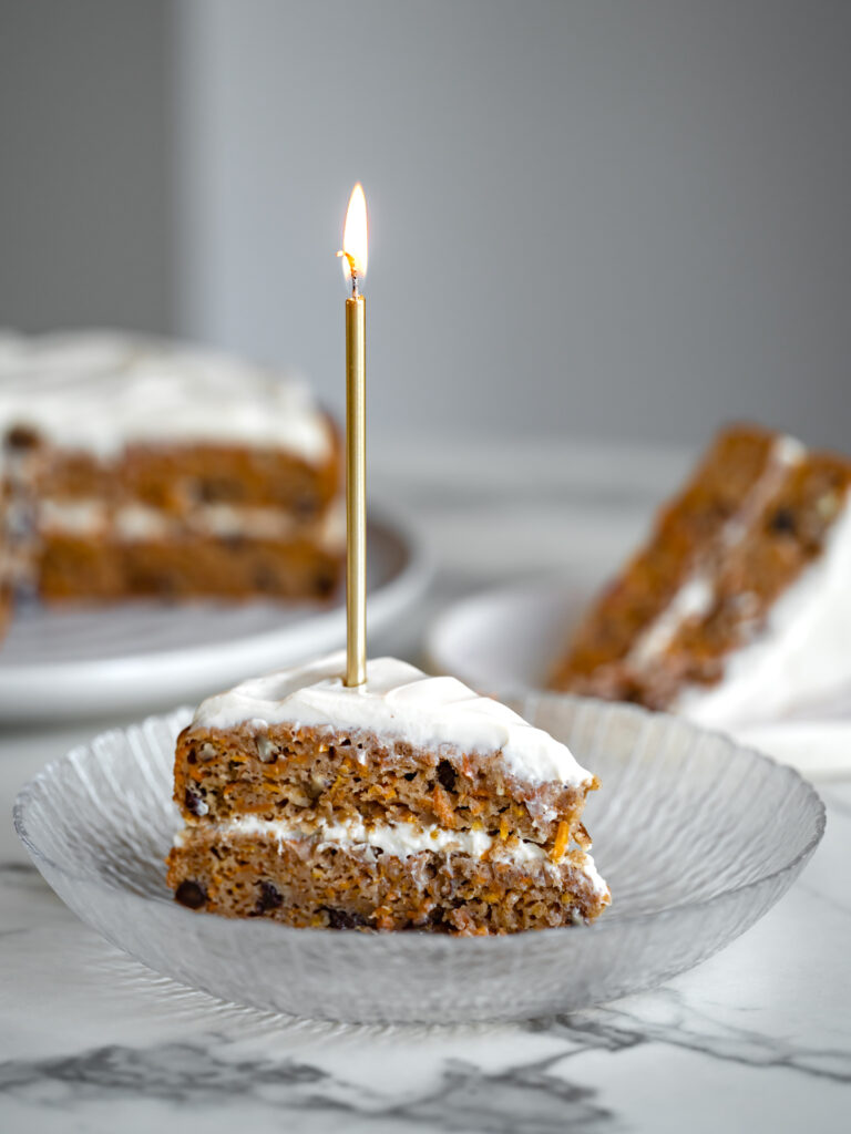 Une pointe généreuse de gâteau aux carottes santé sans sucre raffiné ni gras ajoutés avec une bougie allumée sur le dessus - Bonne fête à notre associé Antoine!