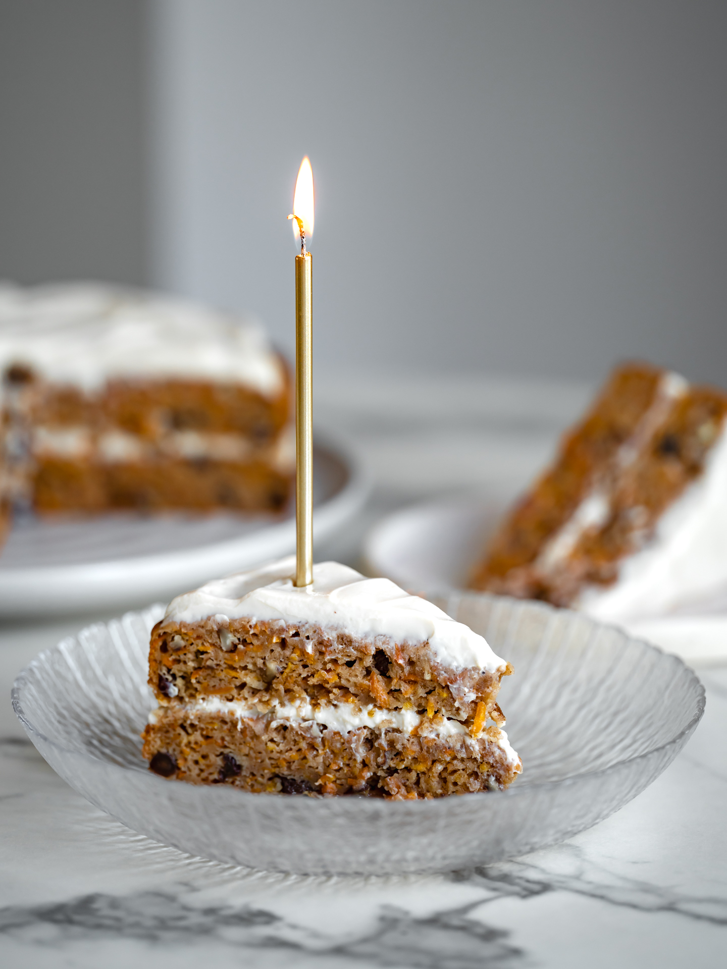 Une pointe généreuse de gâteau aux carottes santé sans sucre raffiné ni gras ajoutés avec une bougie allumée sur le dessus - Bonne fête à notre associé Antoine!