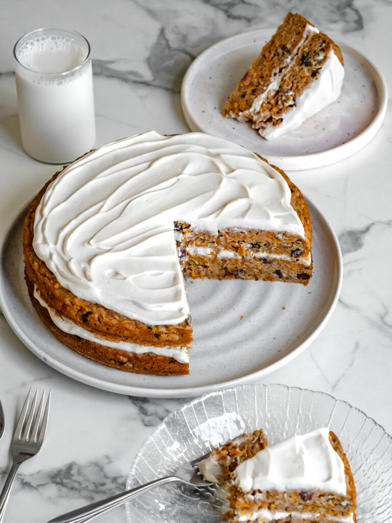 Grande assiette de gâteau aux carottes santé sur la table et pointes de gâteau en train de se faire dévorer